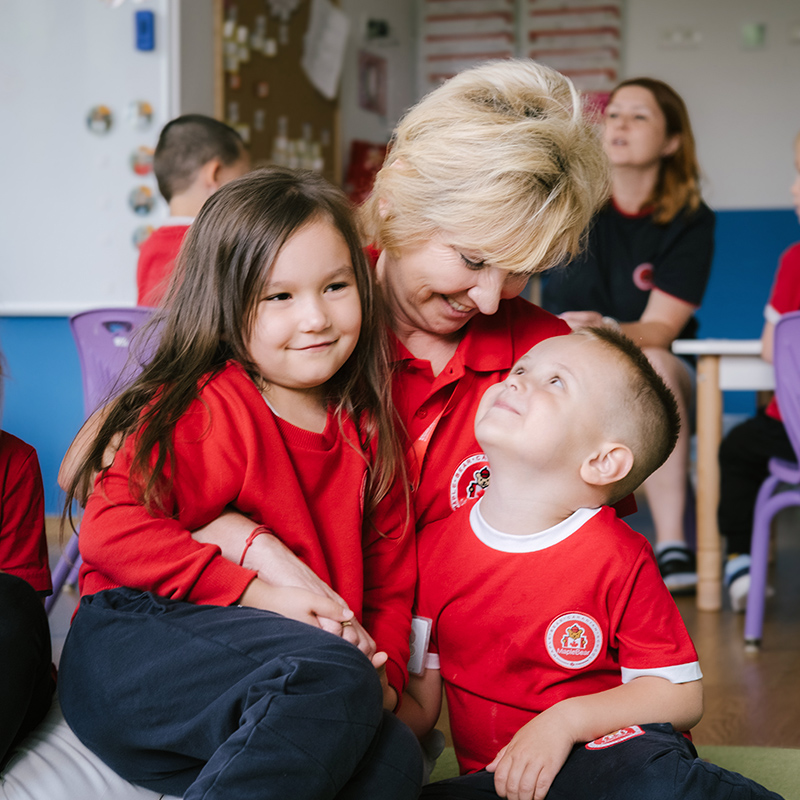 Maple Bear Poland teacher with happy children in red shirts