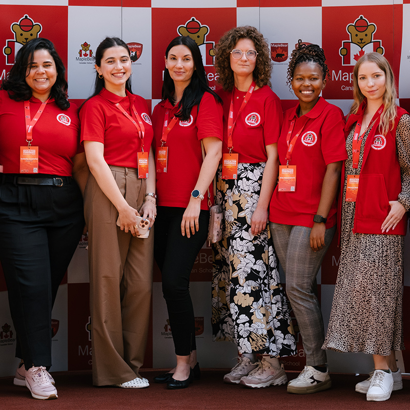 Maple Bear Poland staff in red shirts pose for a photo.