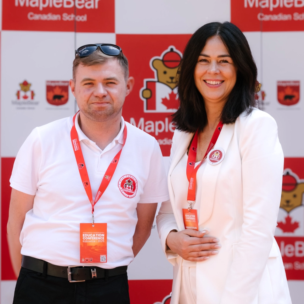 Uśmiechnięta kobieta i mężczyzna na tle logo Maple Bear Canadian School podczas Dni Otwartych Katowice